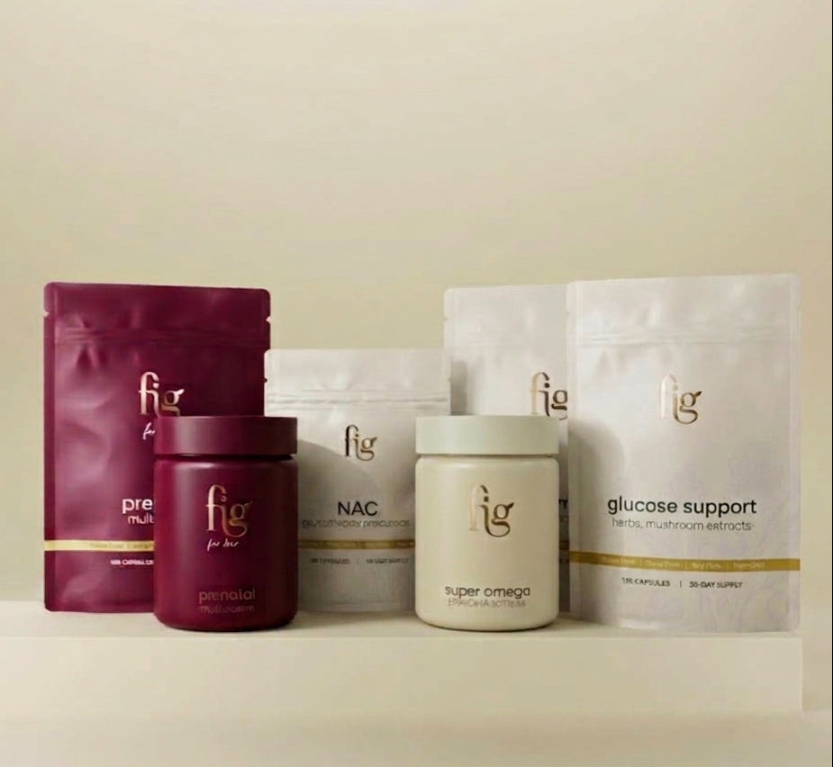 Fig brand health and wellness products arranged on a white platform against a warm beige background. The products include a deep magenta pouch labeled pre-workout, a matching magenta jar labeled personal, white pouches labeled NAC and glucose support, and a cream-colored jar labeled super omega.