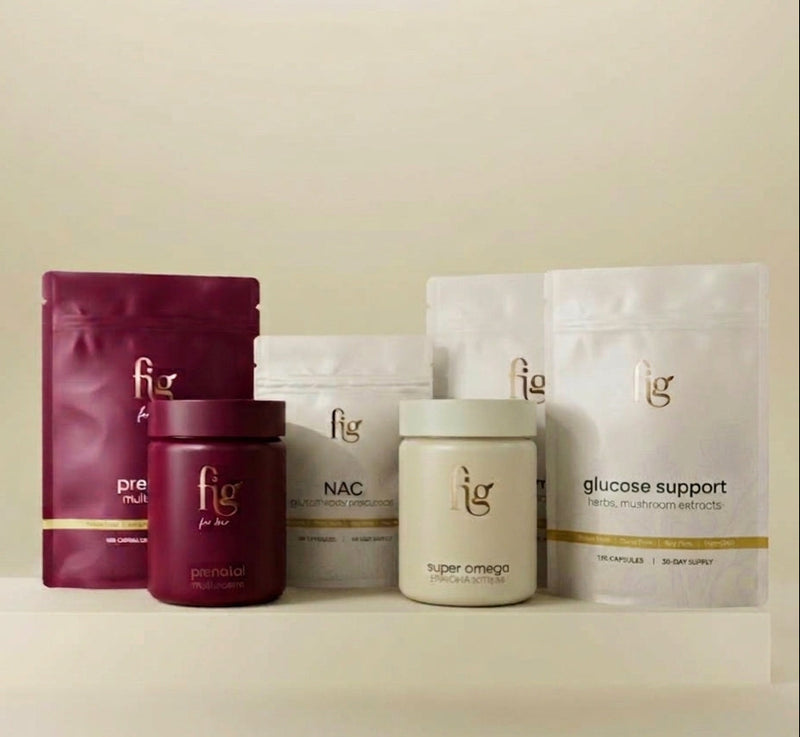 Fig brand health and wellness products arranged on a white platform against a warm beige background. The products include a deep magenta pouch labeled pre-workout, a matching magenta jar labeled personal, white pouches labeled NAC and glucose support, and a cream-colored jar labeled super omega.